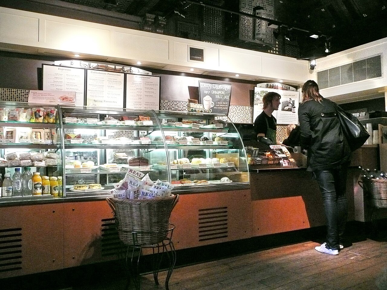Eine Frau steht an der Theke eines Cafés, dahinter eine Mitarbeiterin.